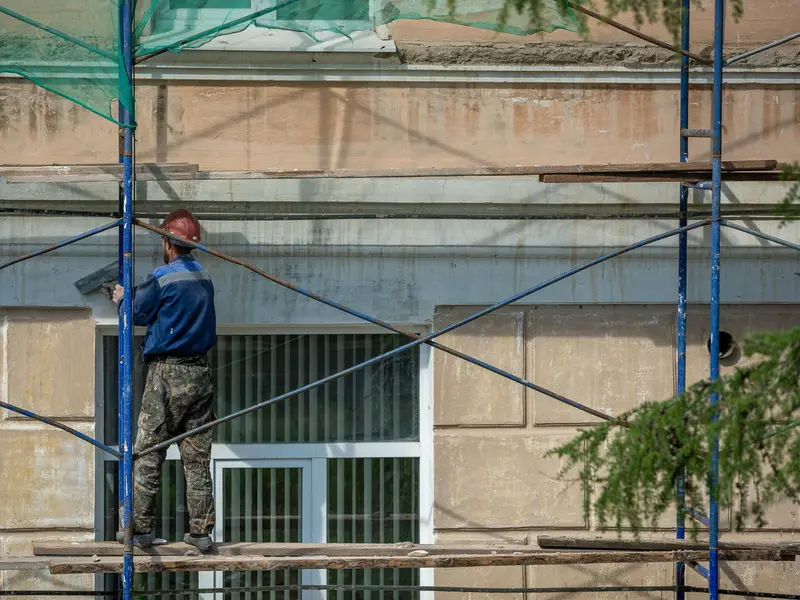 Majstor na skeli obnavlja fasadu zgrade